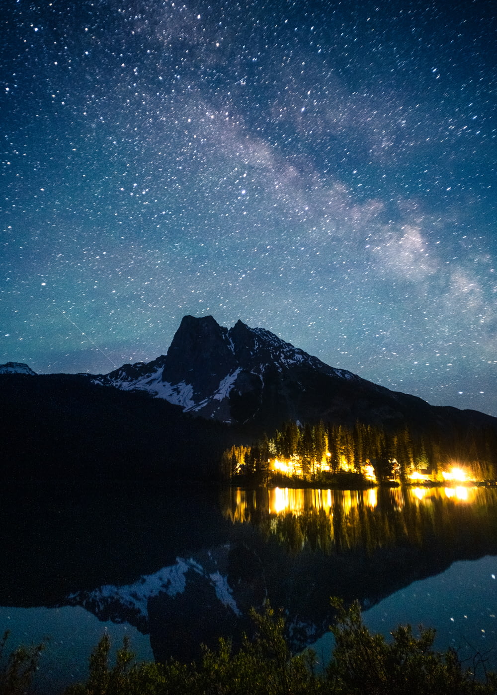 a lake with a mountain and stars in the sky