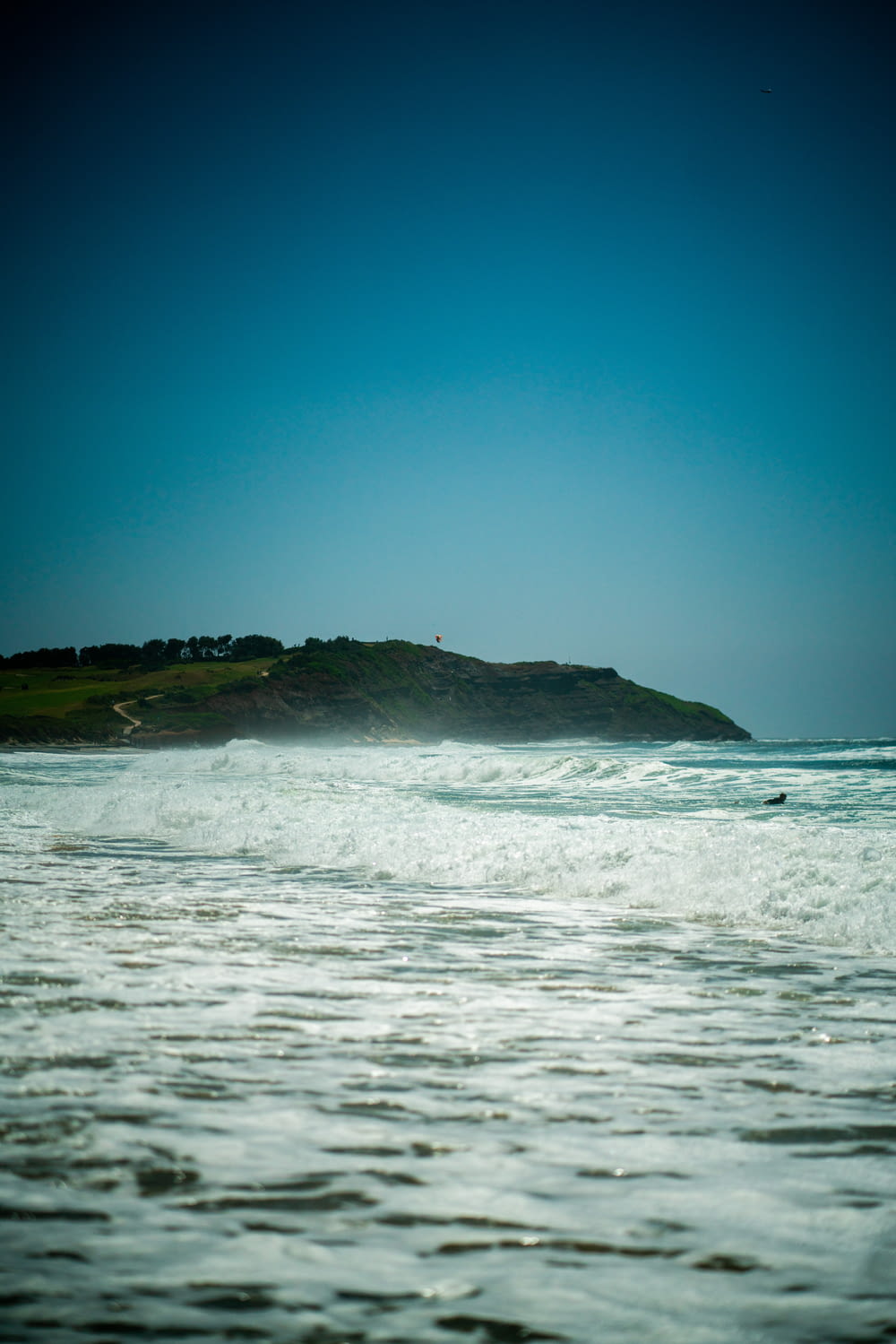 a body of water with waves and a hill in the background