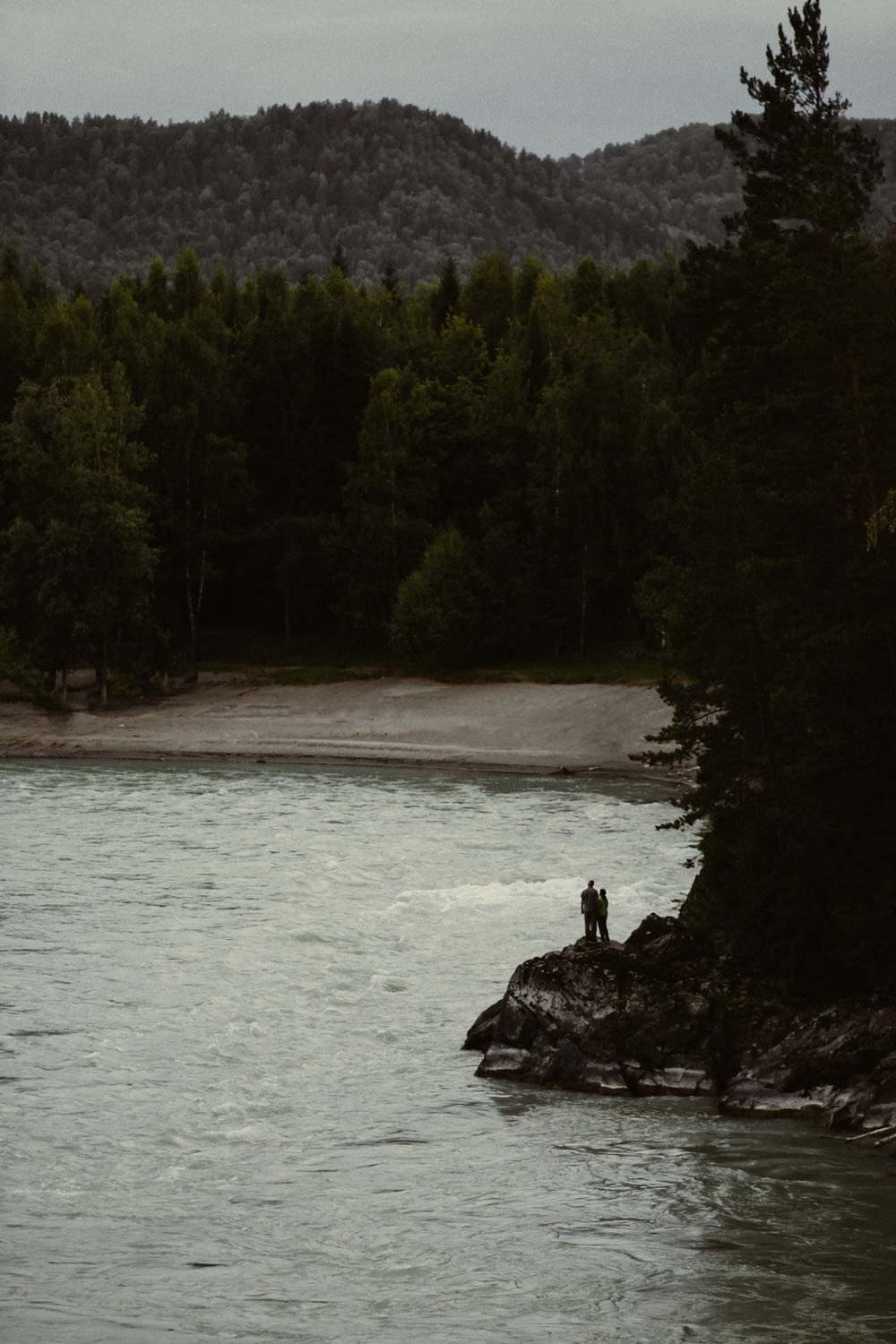 una persona in piedi su una roccia in un lago