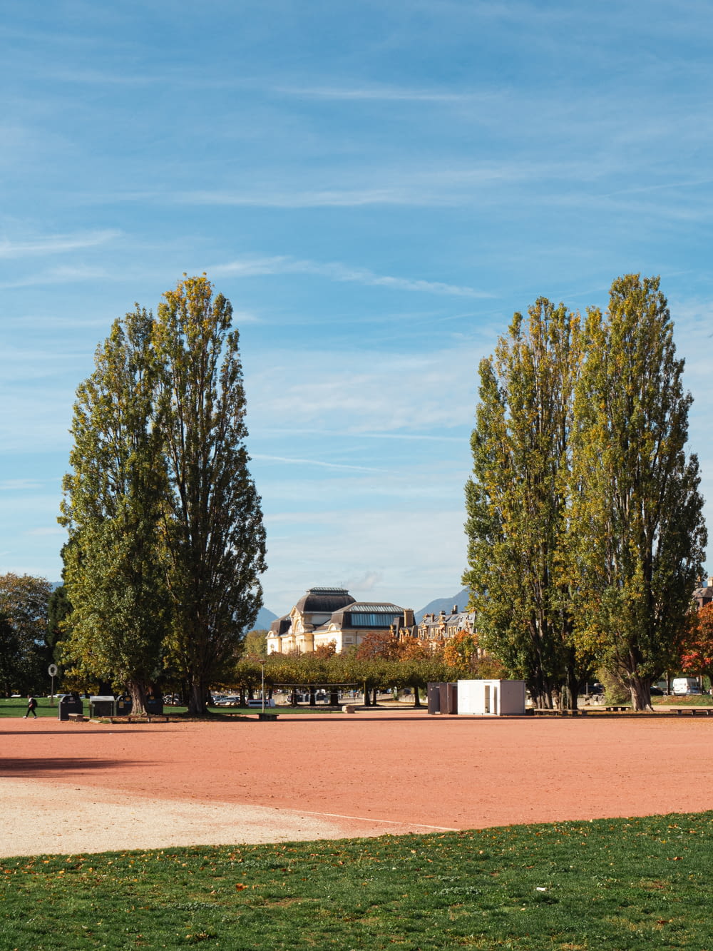 a large green field with trees and a building in the background