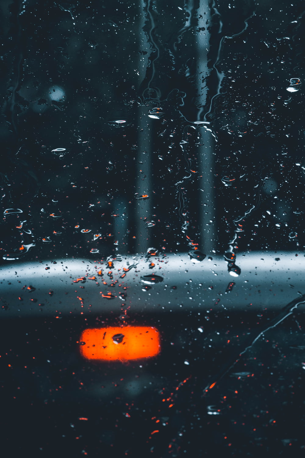 a rain covered window with a traffic light in the background