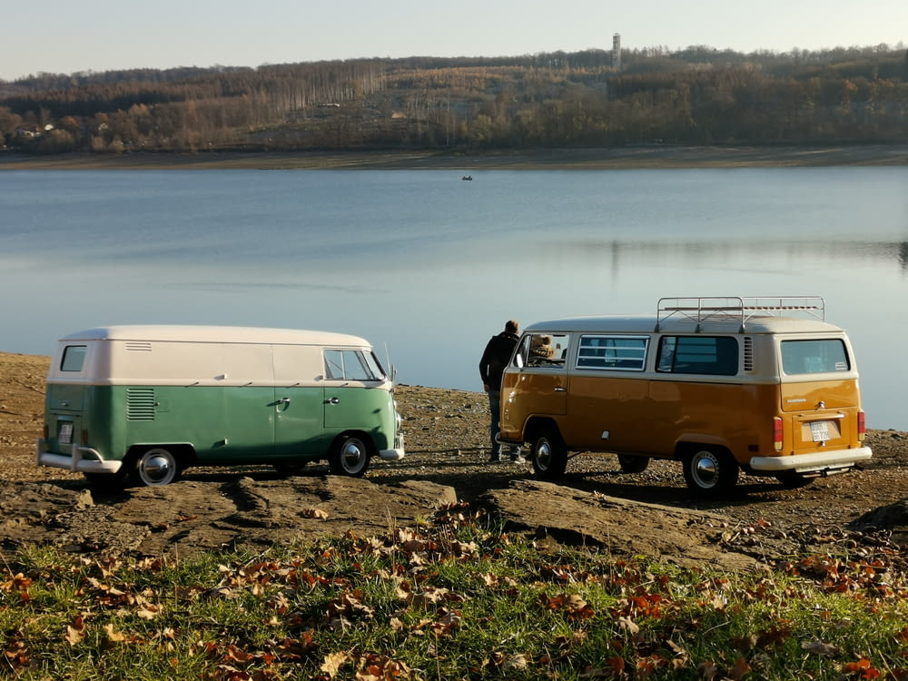 a couple of vans parked next to each other near a body of water