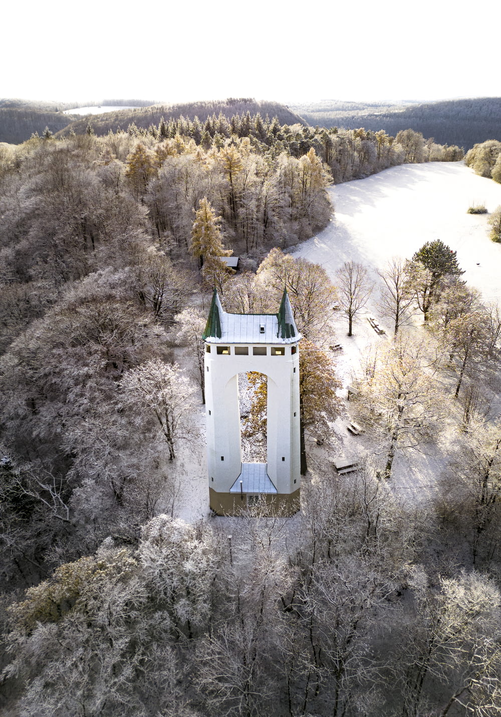 an aerial view of a white building surrounded by trees