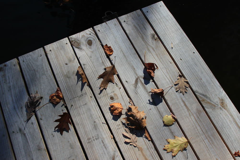 a wooden deck with leaves on it