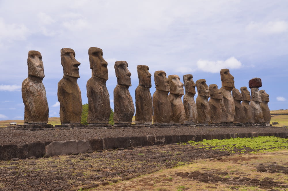 a row of moai statues sitting on top of a grass covered field