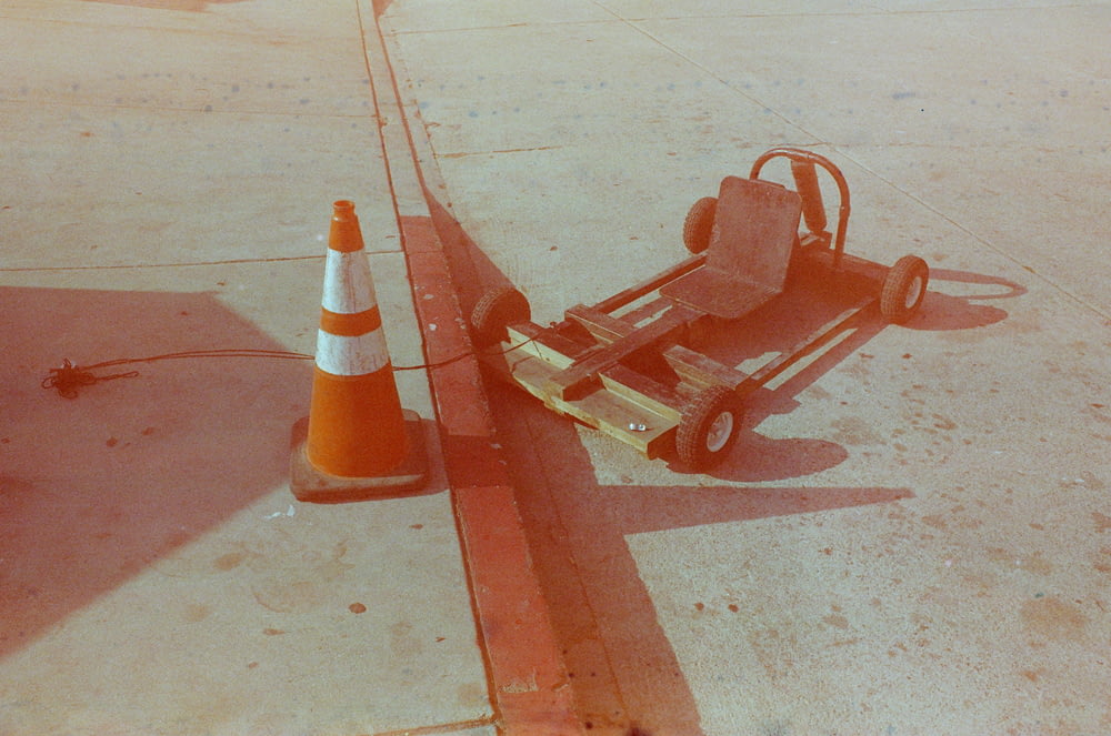 a small cart sitting on the side of a road next to a traffic cone