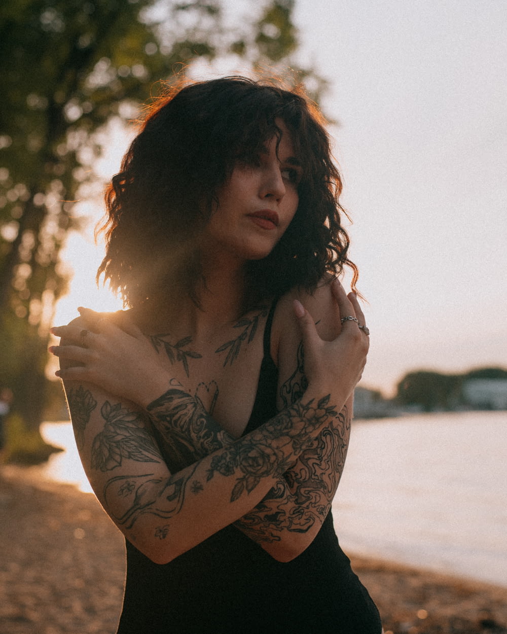 a woman with tattoos standing on a beach