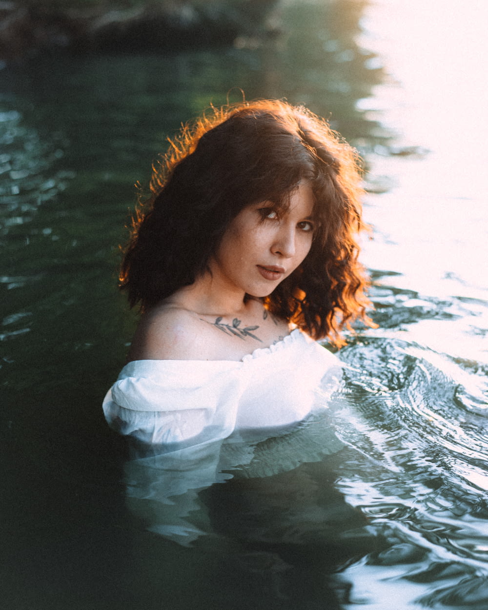 a woman in a body of water wearing a white shirt