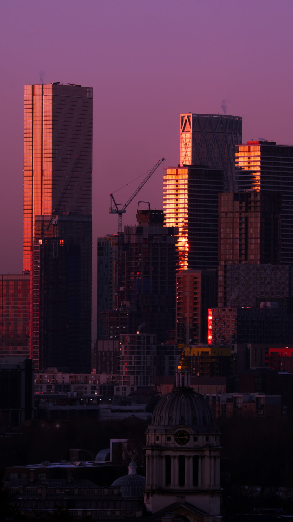 a city skyline with tall buildings and a crane in the background