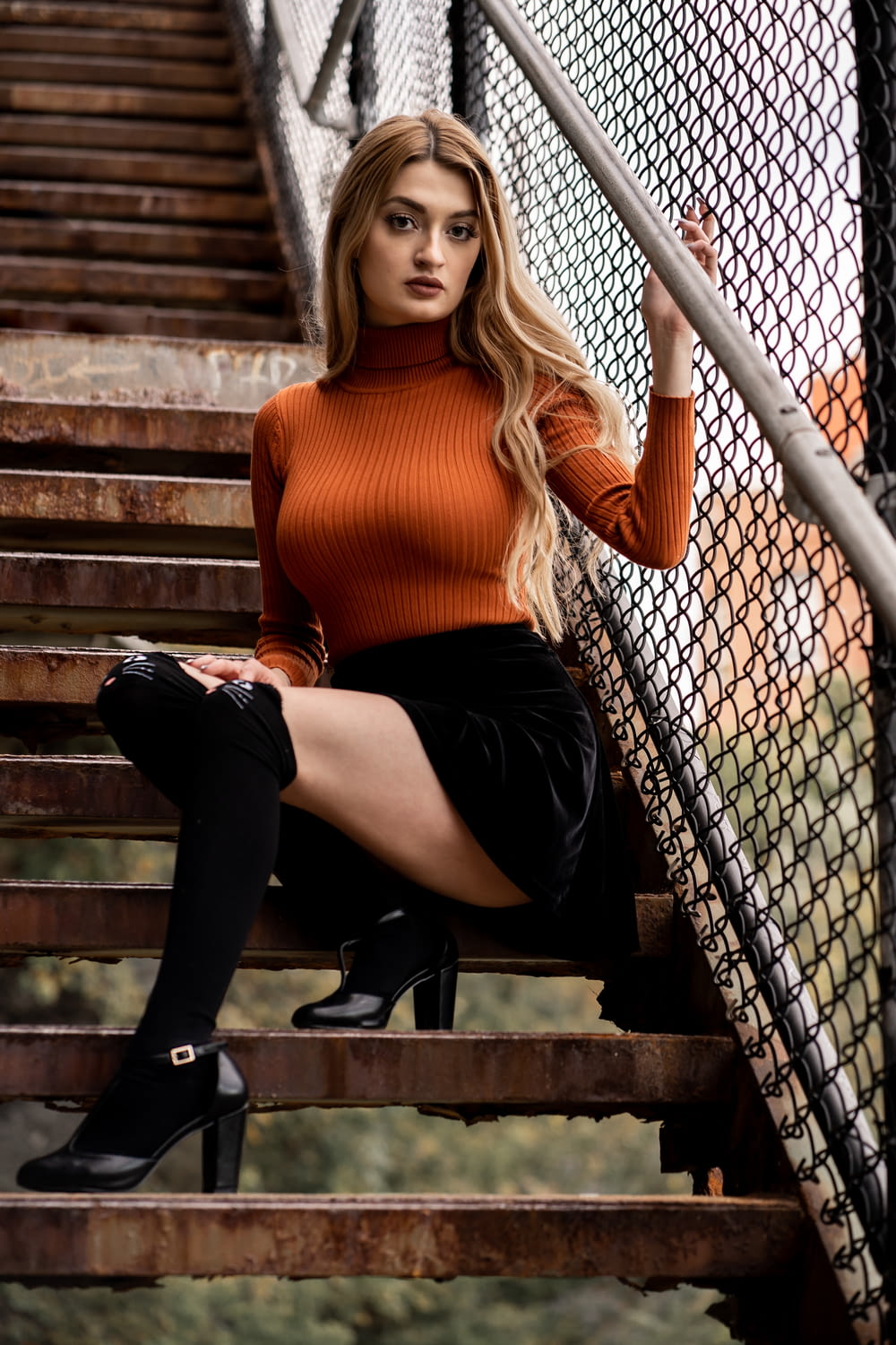 a beautiful young woman sitting on top of a set of stairs