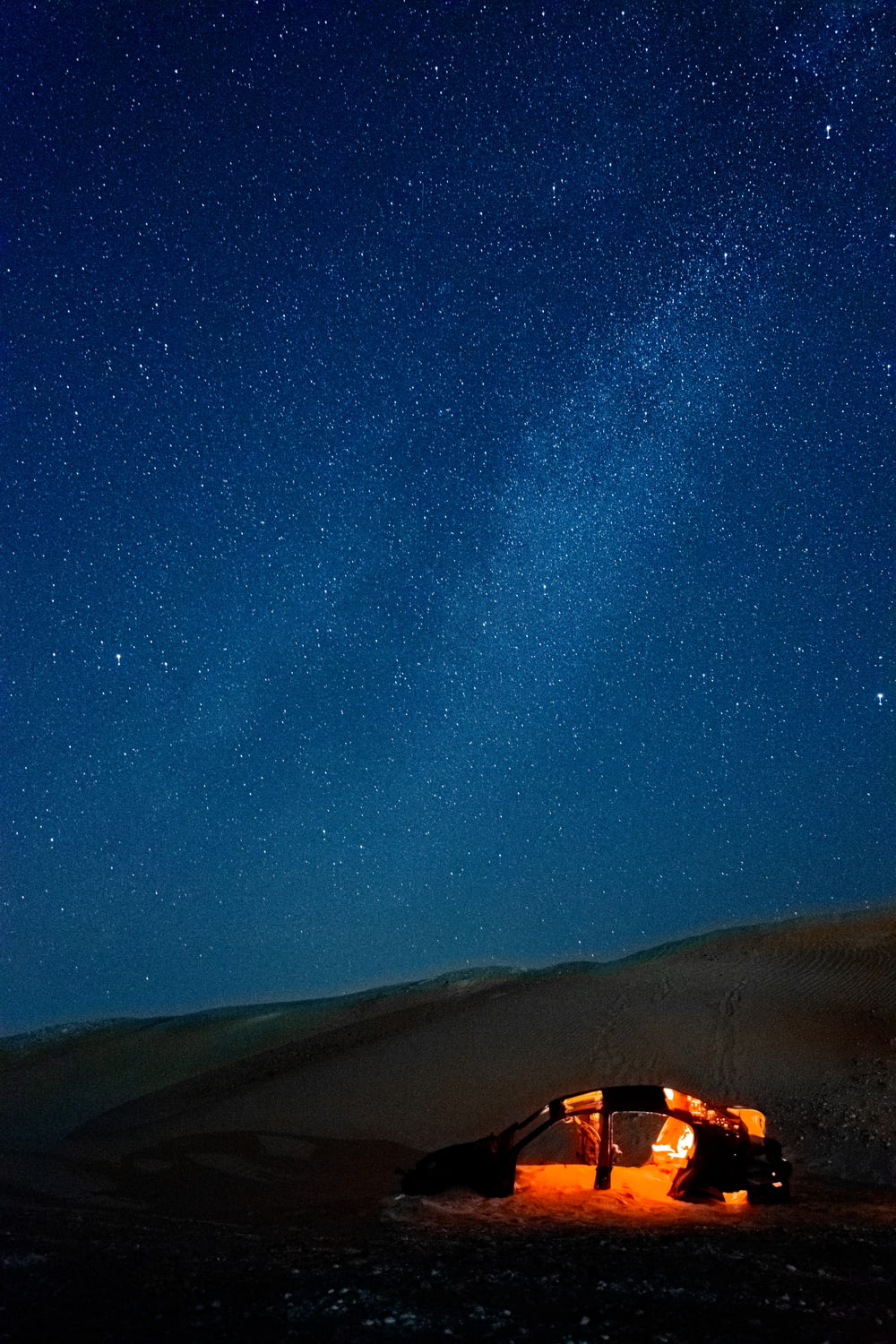 a tent in the middle of a desert under a night sky filled with stars