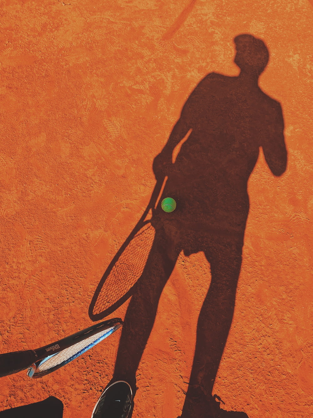 Ein Schatten eines Mannes, der einen Tennisschläger hält