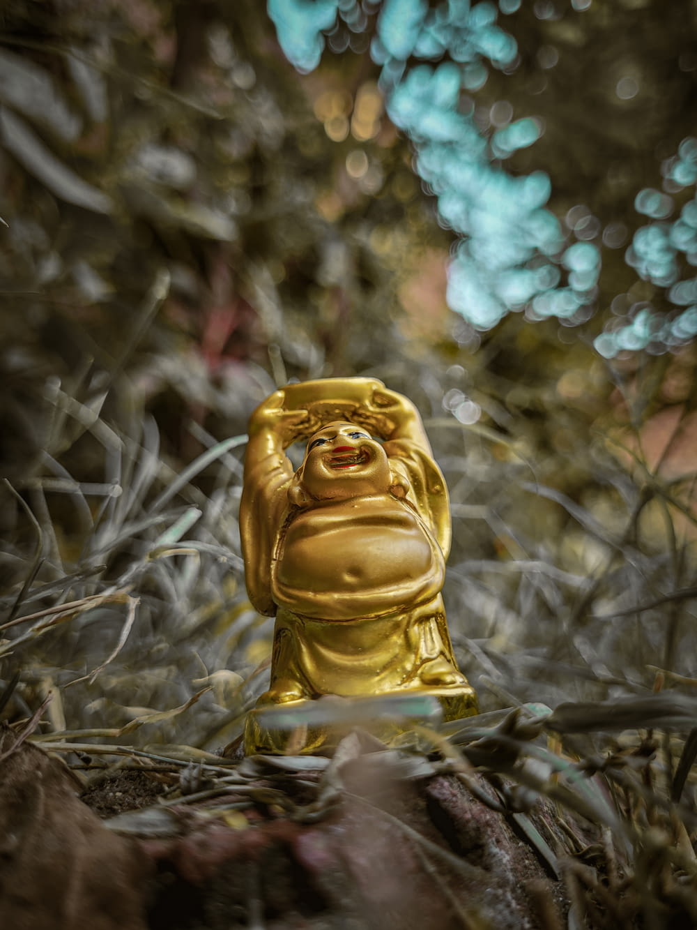 a gold buddha statue sitting in the middle of a forest