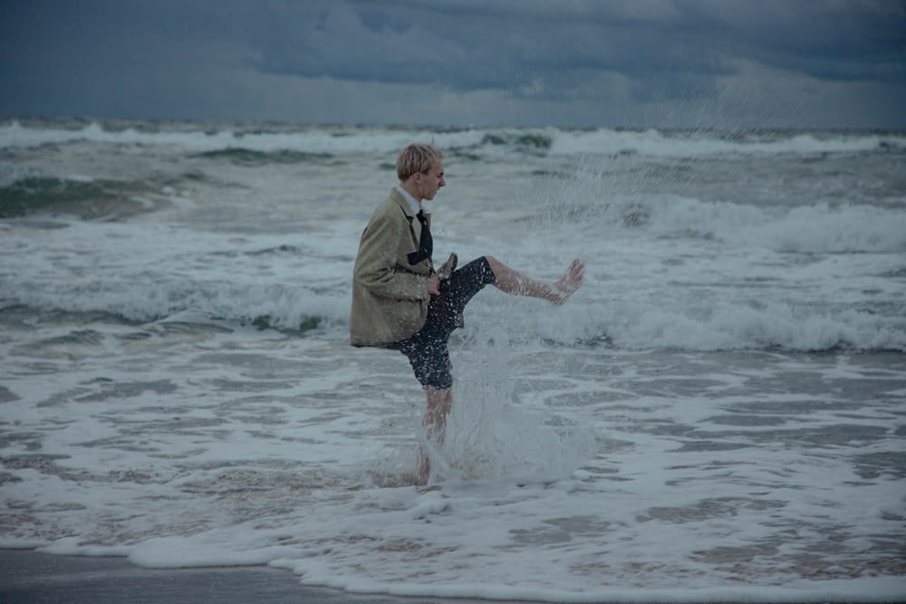 a man standing in the ocean with his feet in the water