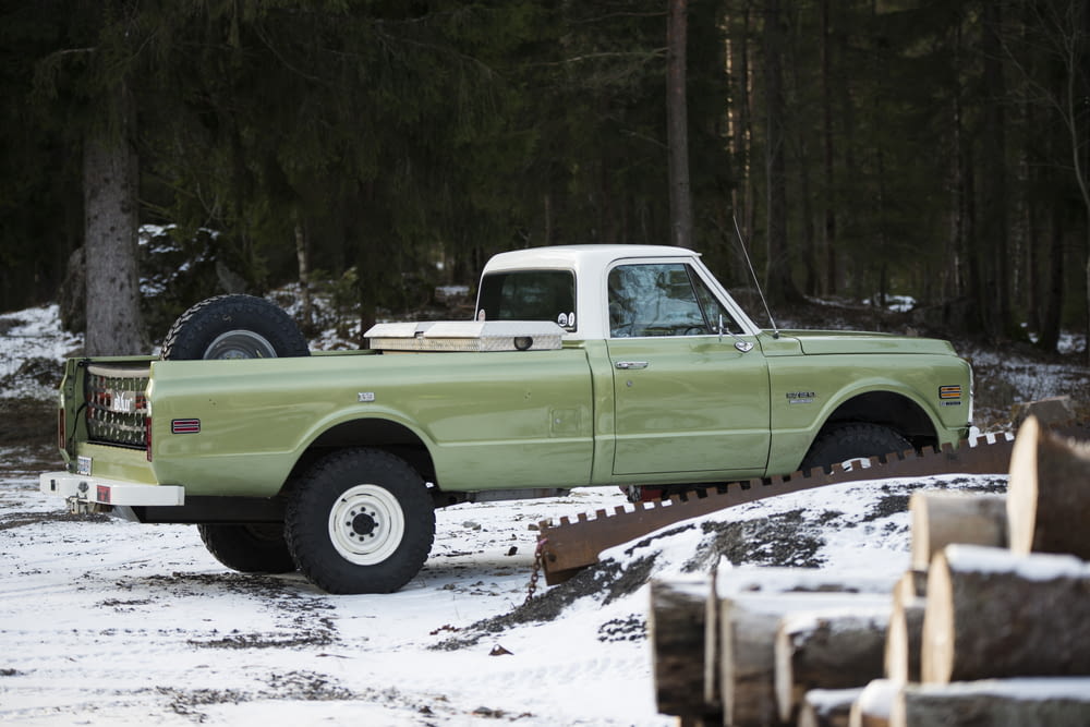 a green pick up truck parked in the snow