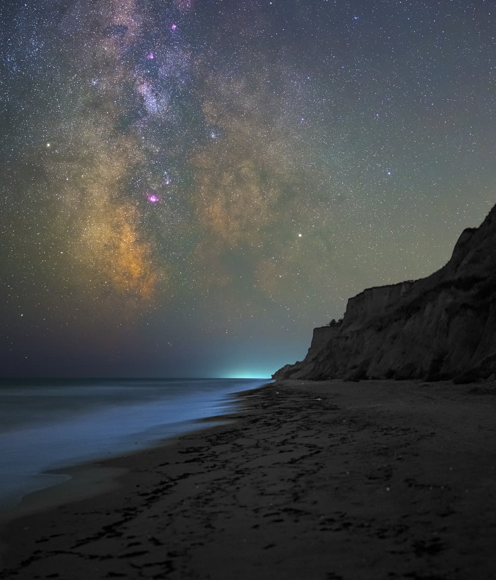 the night sky is filled with stars above the ocean