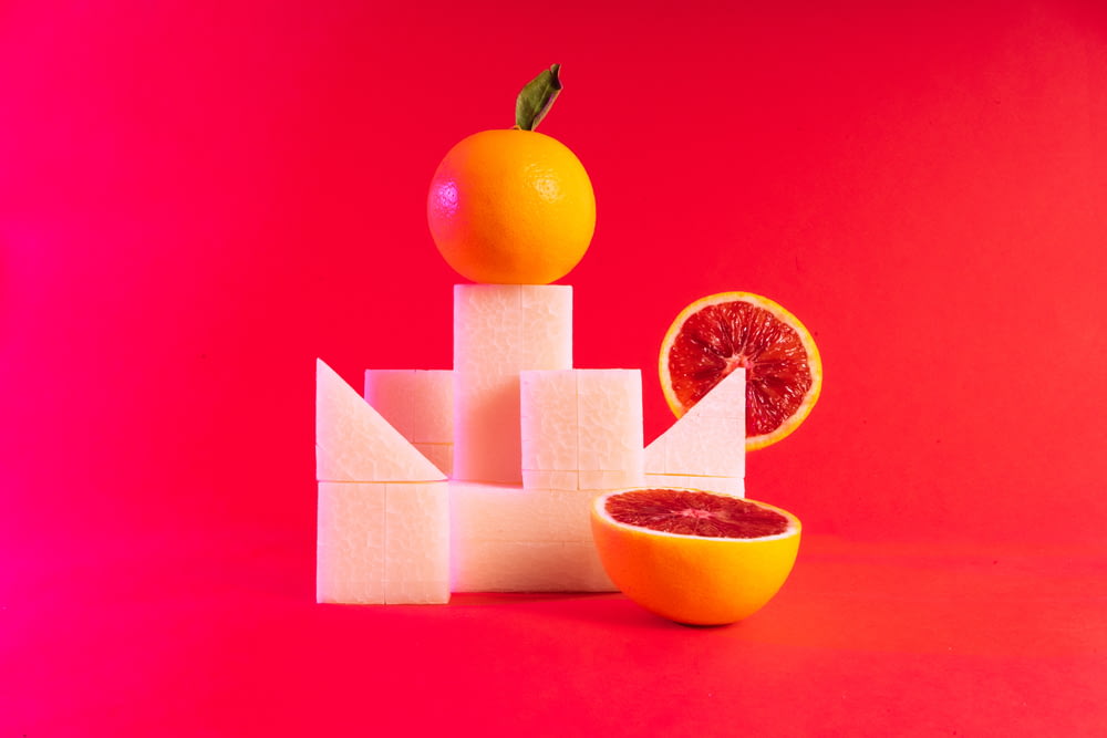 an orange sitting on top of a block of cheese next to a grapefruit