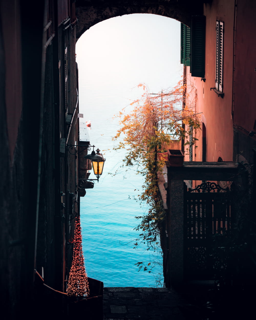 an alley way with a lamp post and a body of water in the distance