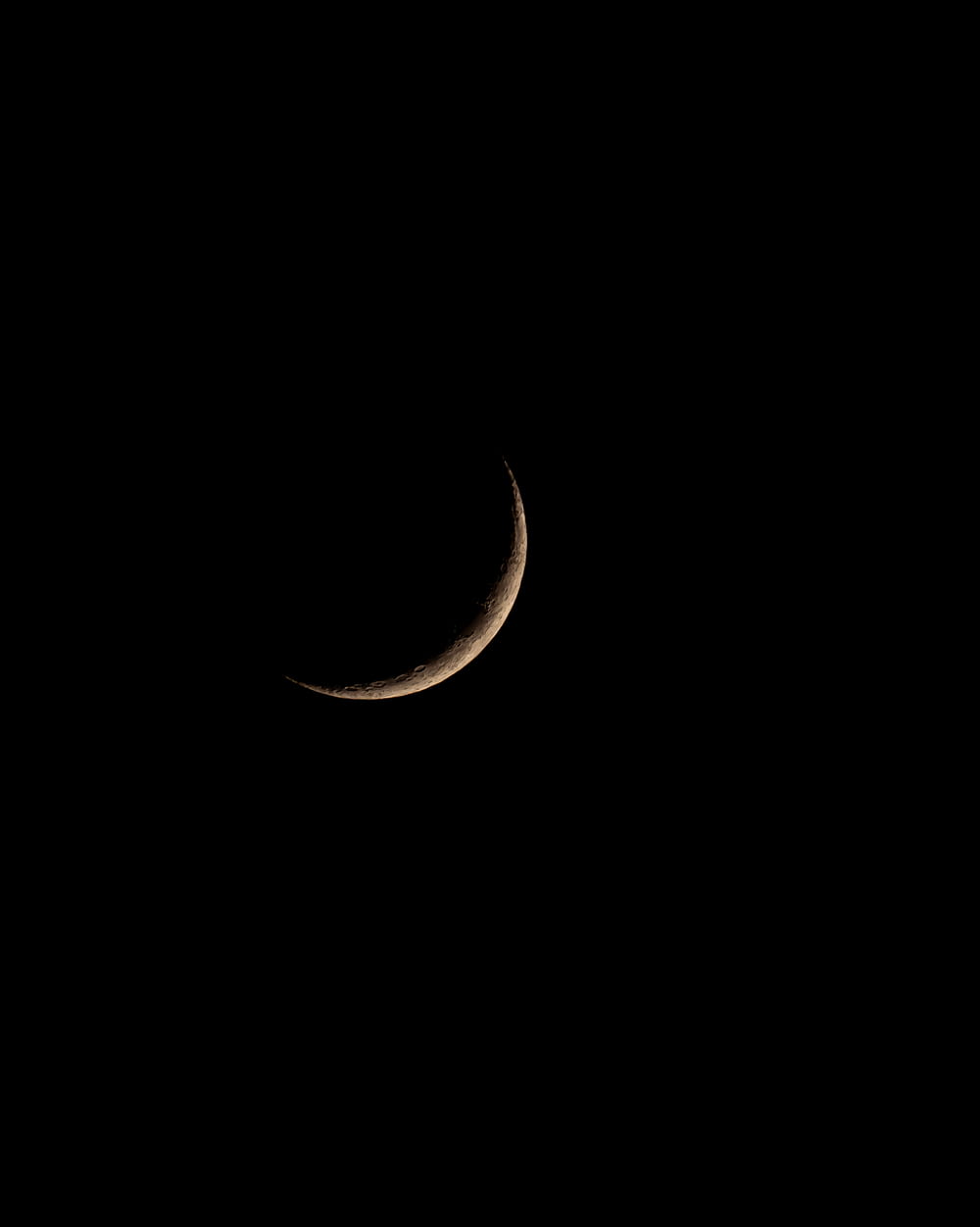 a crescent moon is seen in the dark sky