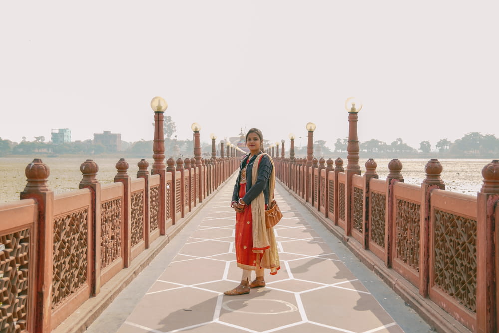 a woman standing on a bridge over a body of water