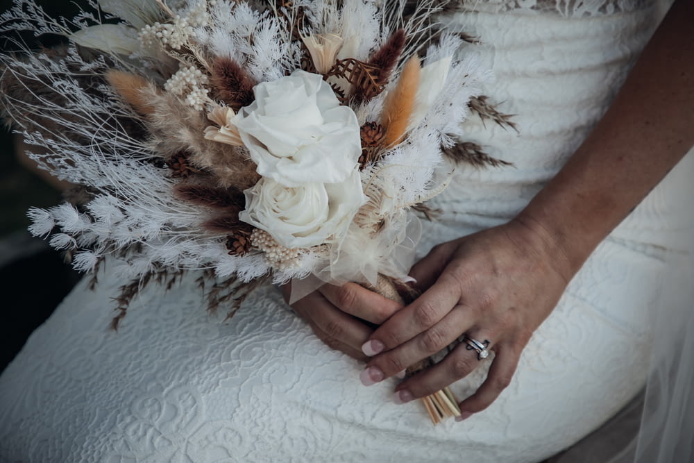 a bride holding a bouquet of flowers and feathers