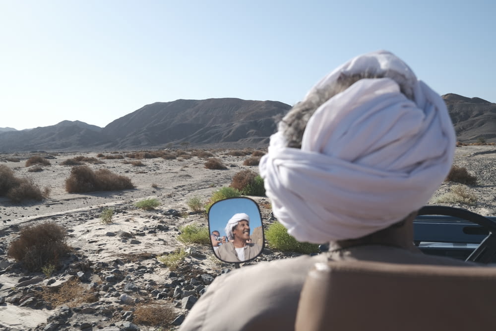 a man with a turban looking at a picture of himself in a mirror