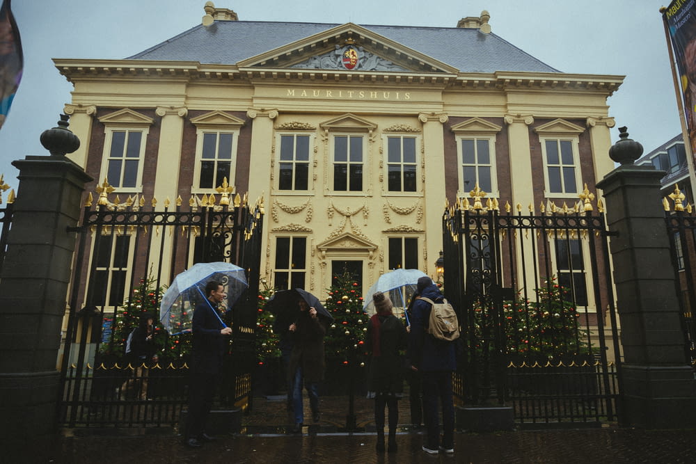 a group of people holding umbrellas standing in front of a building