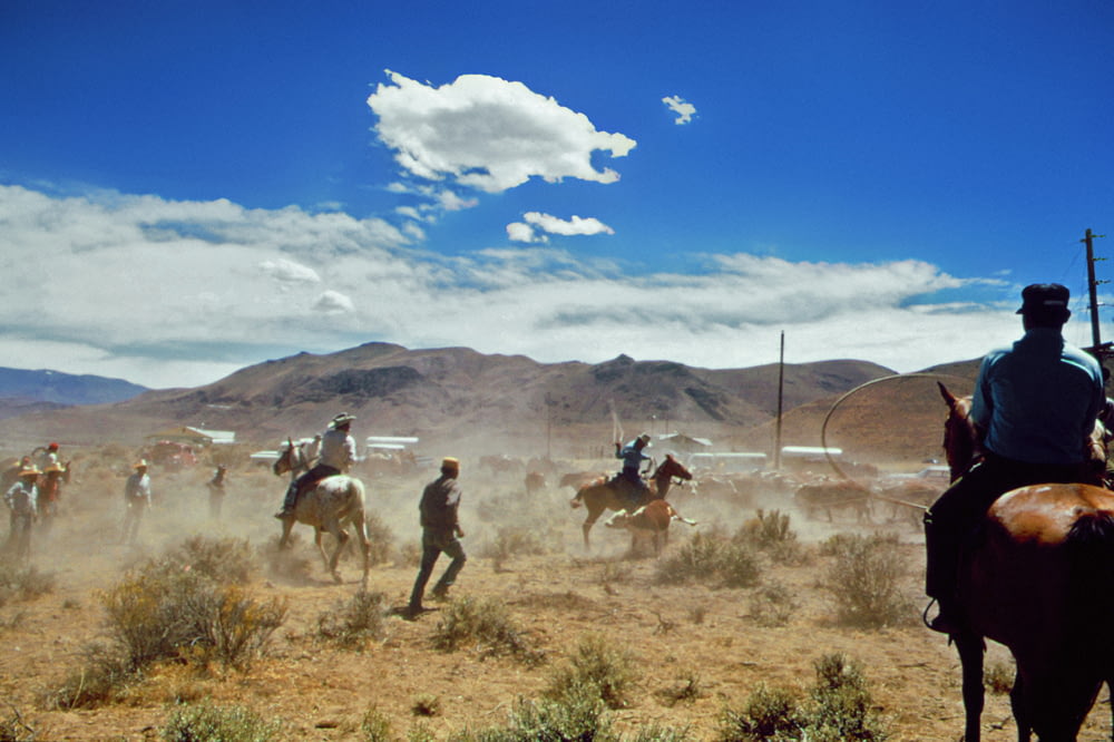 a group of men riding horses through a desert