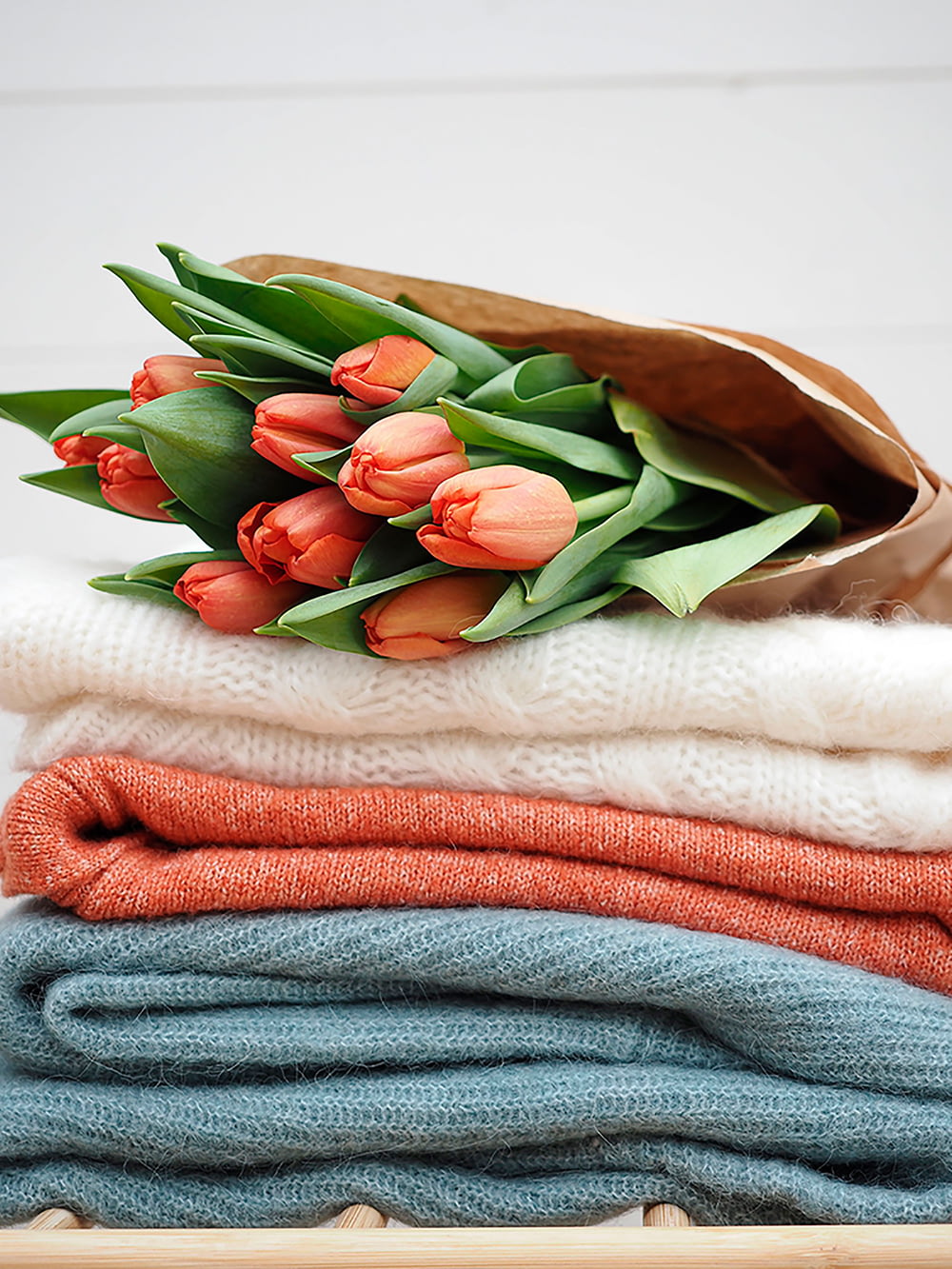 a bunch of tulips sitting on top of a pile of sweaters