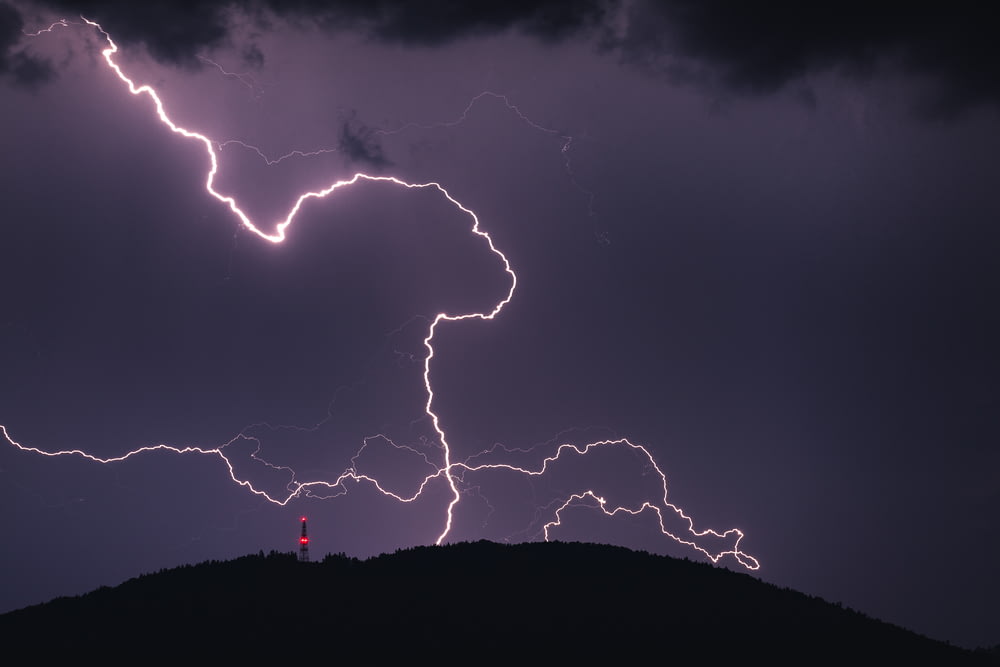 a couple of lightning strikes over a hill