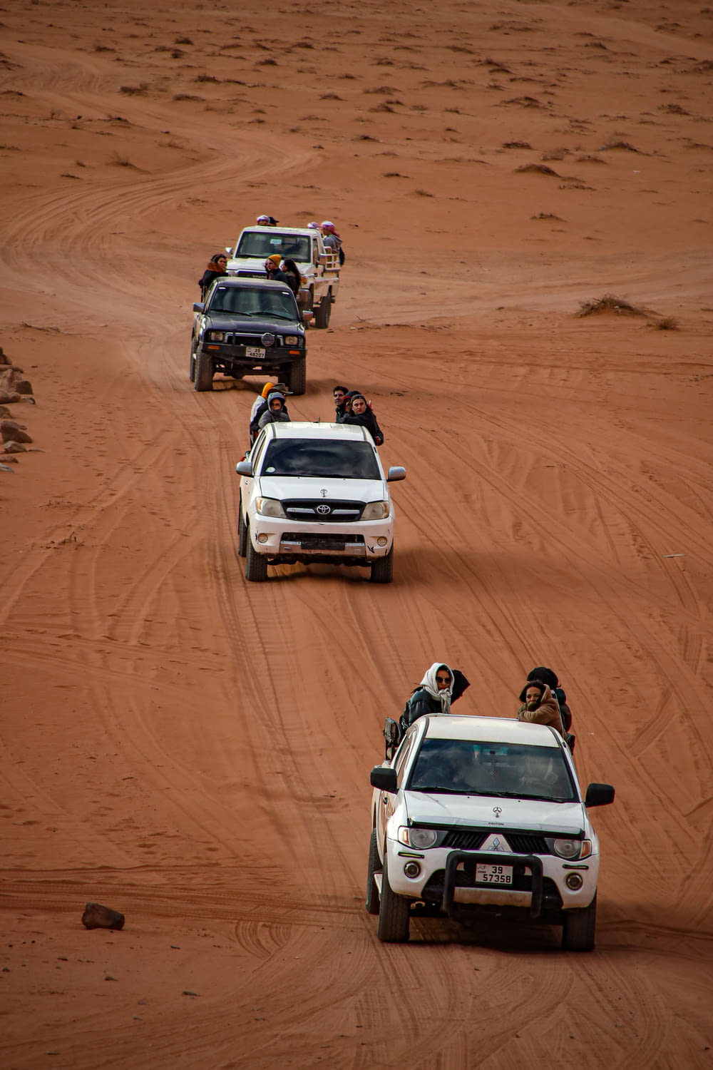 a group of vehicles driving down a dirt road