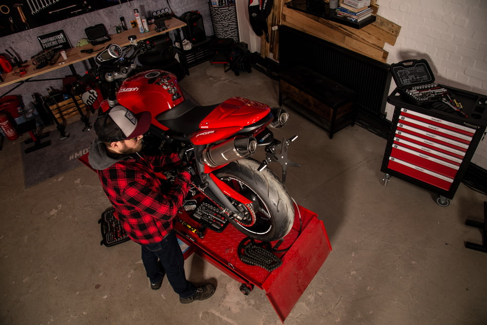 a man standing next to a red motorcycle in a garage