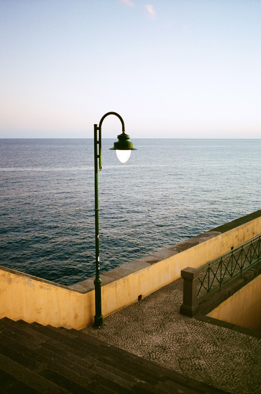 a street light sitting on the side of a wall next to the ocean