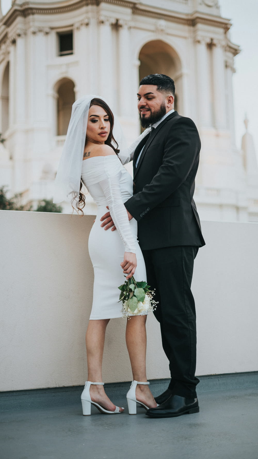 a bride and groom pose for a photo in front of the state capitol building