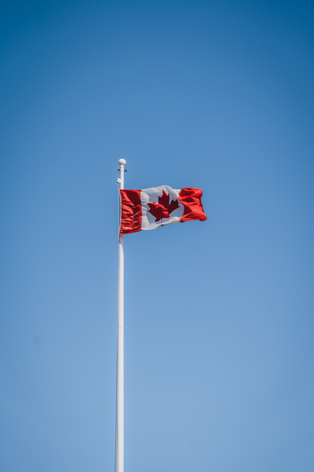 a canadian flag flying high in the sky