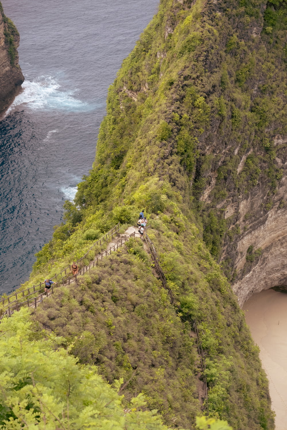 Un gruppo di persone che camminano su una ripida collina vicino all'oceano