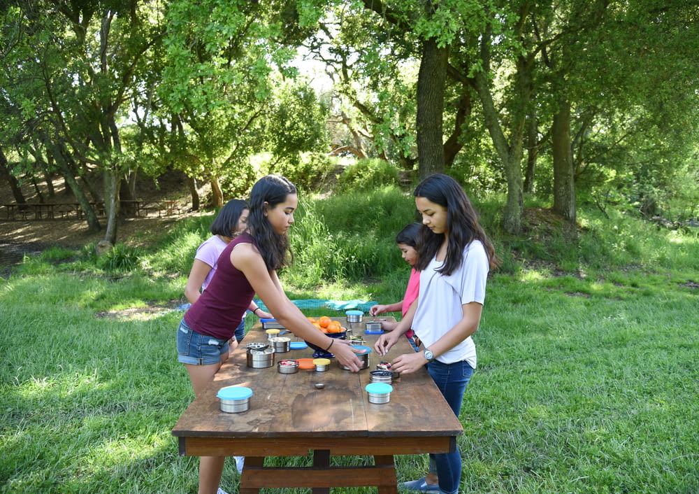 a group of girls standing around a picnic table