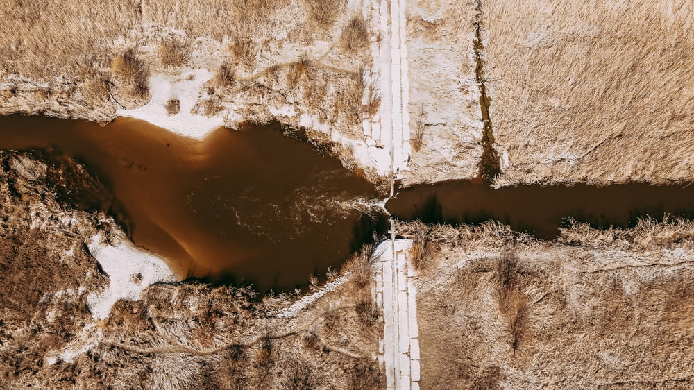 an aerial view of a dirt road and a puddle of water