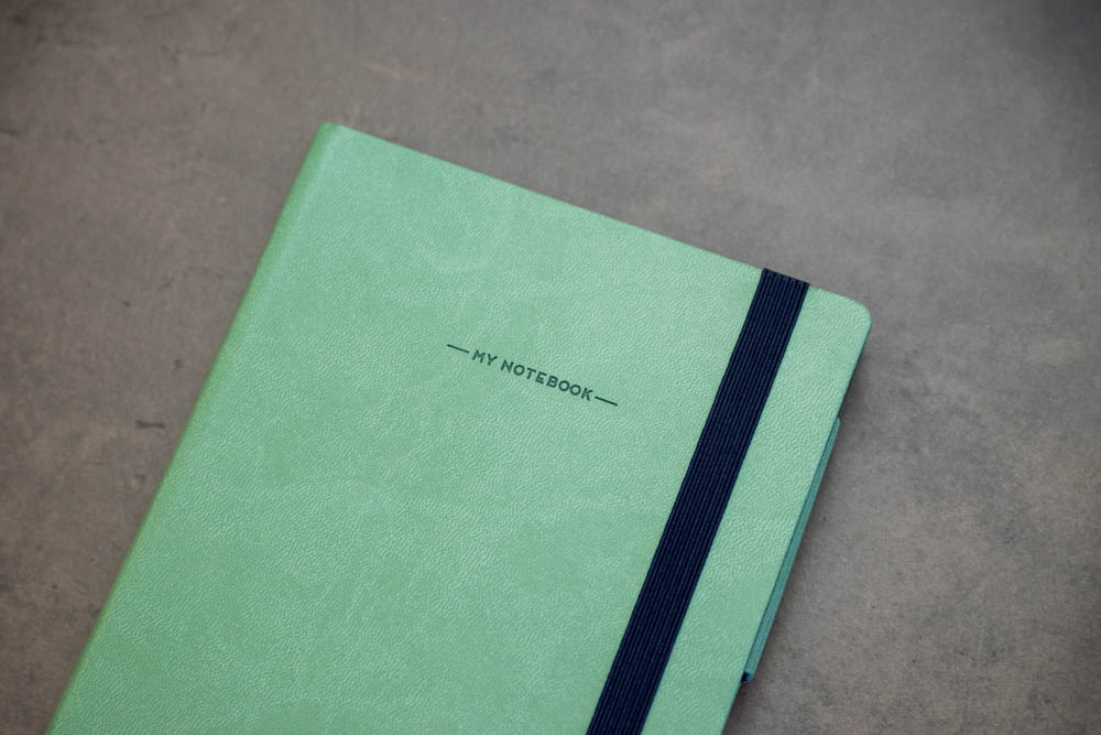 a green notebook with a black stripe on the cover
