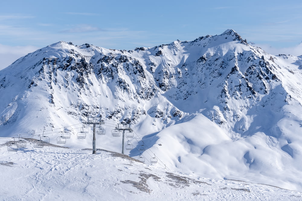 uma montanha coberta de neve com um teleférico em primeiro plano