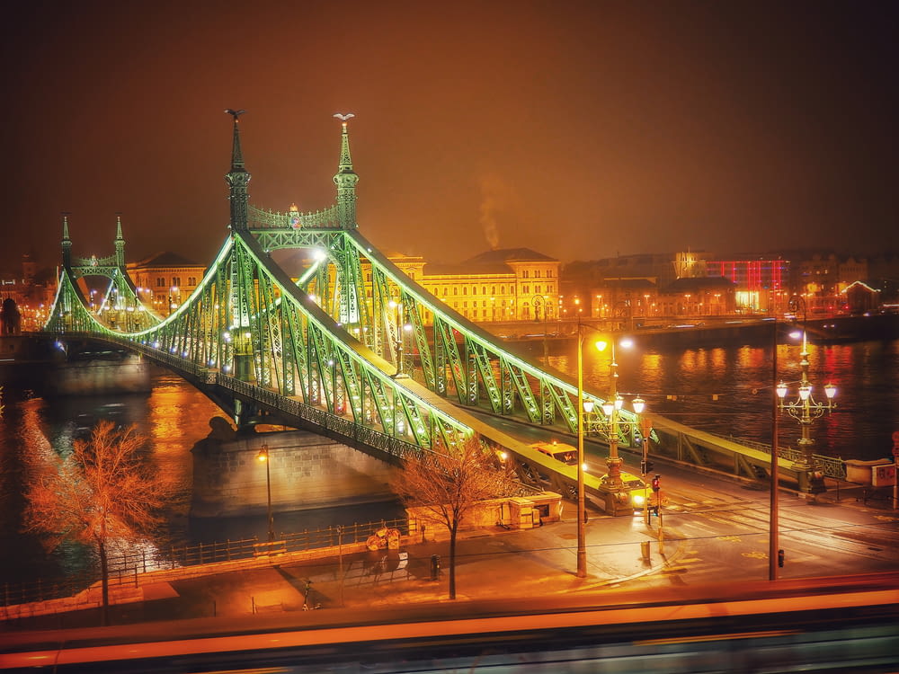 a large green bridge over a river at night