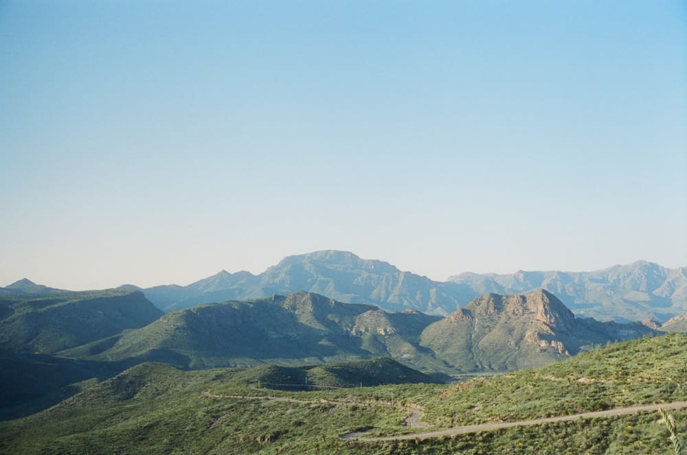 a scenic view of a mountain range with a winding road in the foreground
