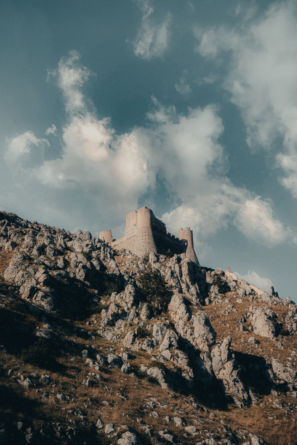 a castle sitting on top of a mountain under a cloudy sky