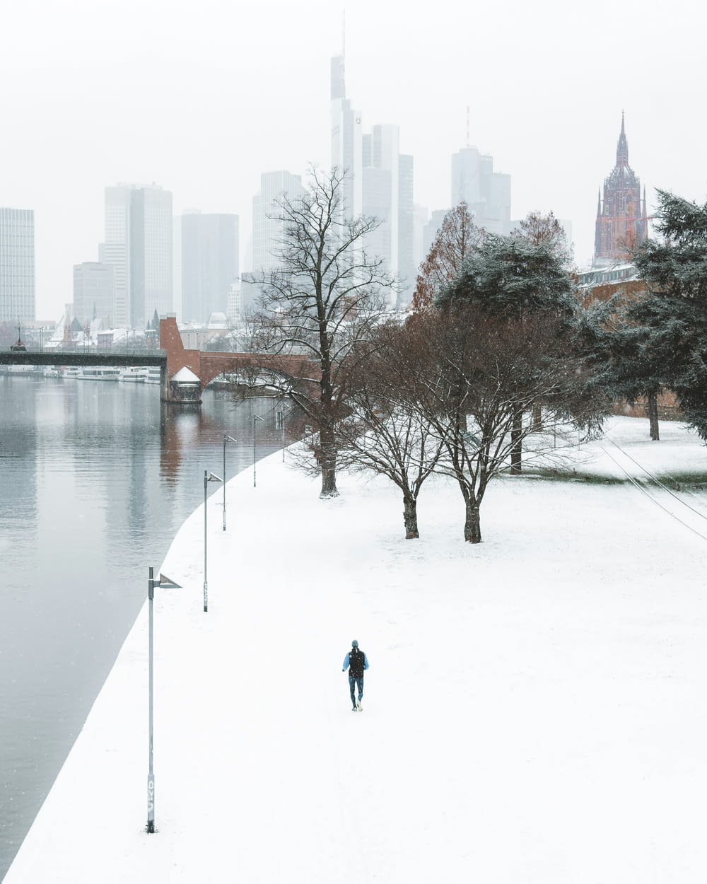 a person walking in the snow next to a body of water