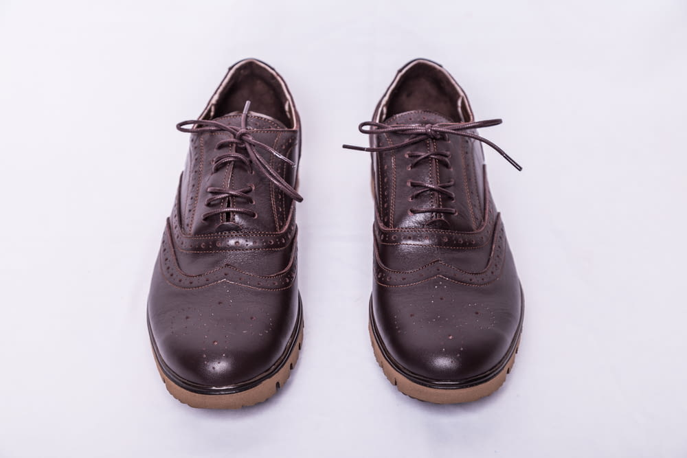 a pair of brown shoes on a white surface