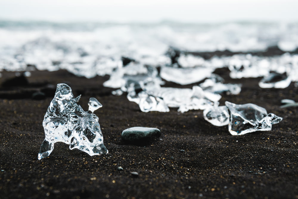 a group of ice pieces sitting on top of a black sand beach