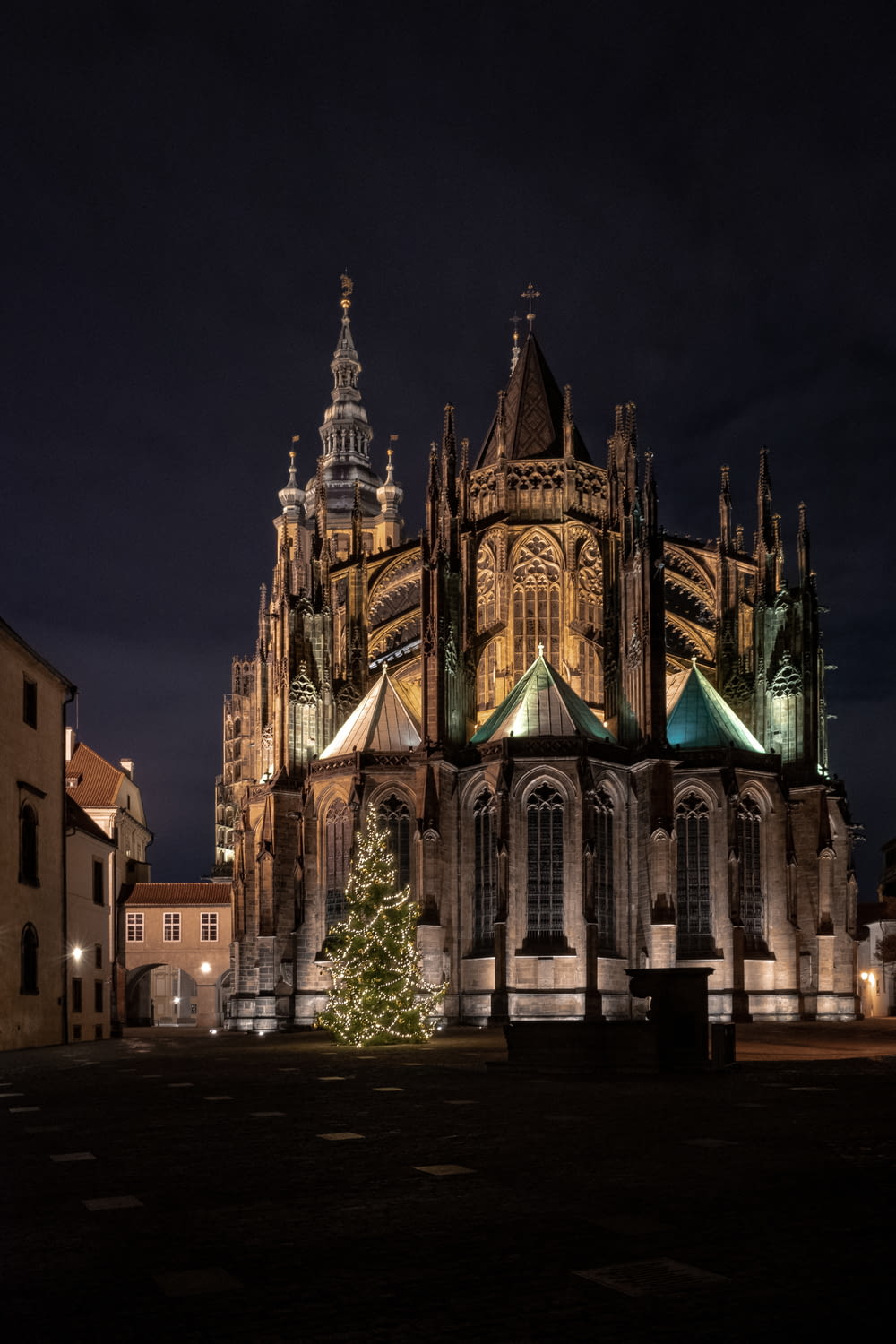 a large cathedral lit up at night with a christmas tree in front of it
