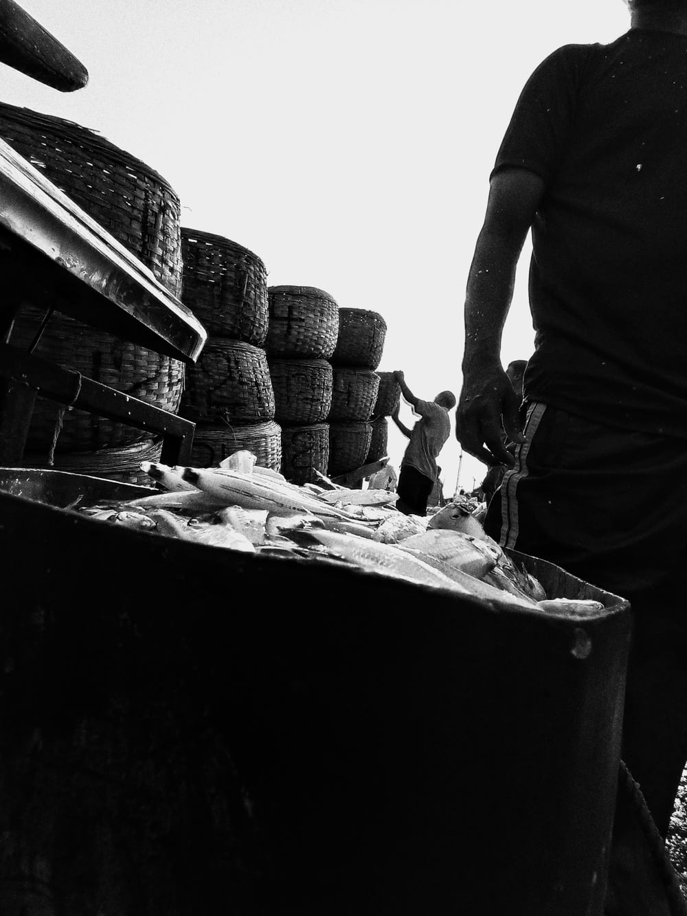 a black and white photo of a man standing next to a bin full of tires