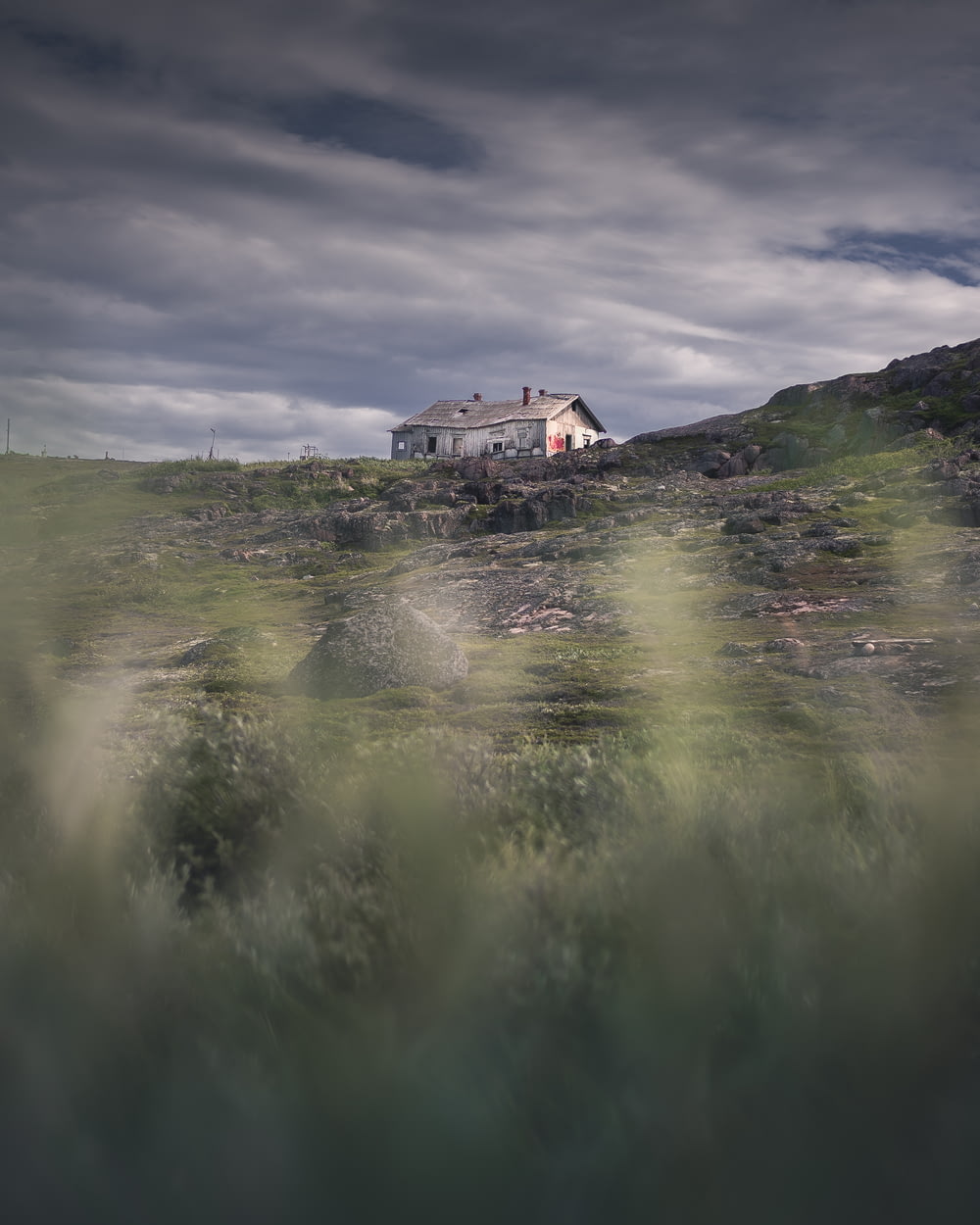 a house sitting on top of a hill under a cloudy sky
