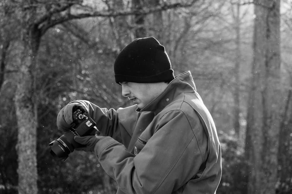 a black and white photo of a man holding a camera